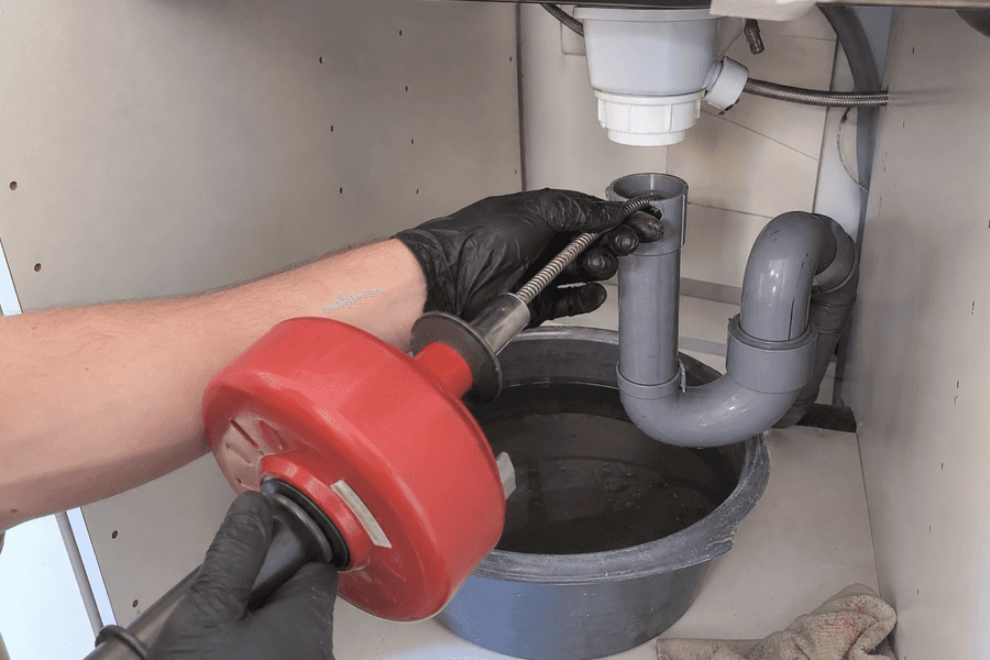 furet manuel inséré dans canalisation sous évier mains