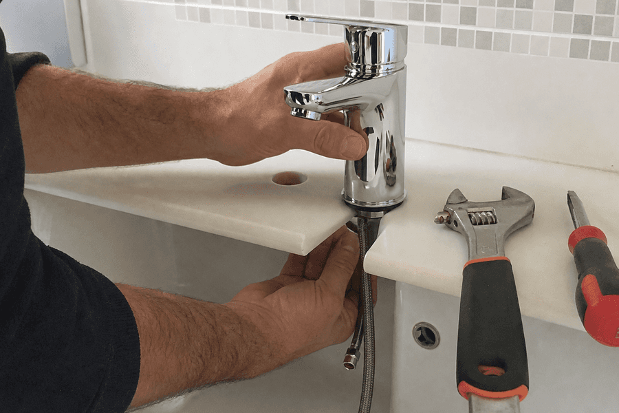 mains installant mitigeur neuf sur lavabo raccords